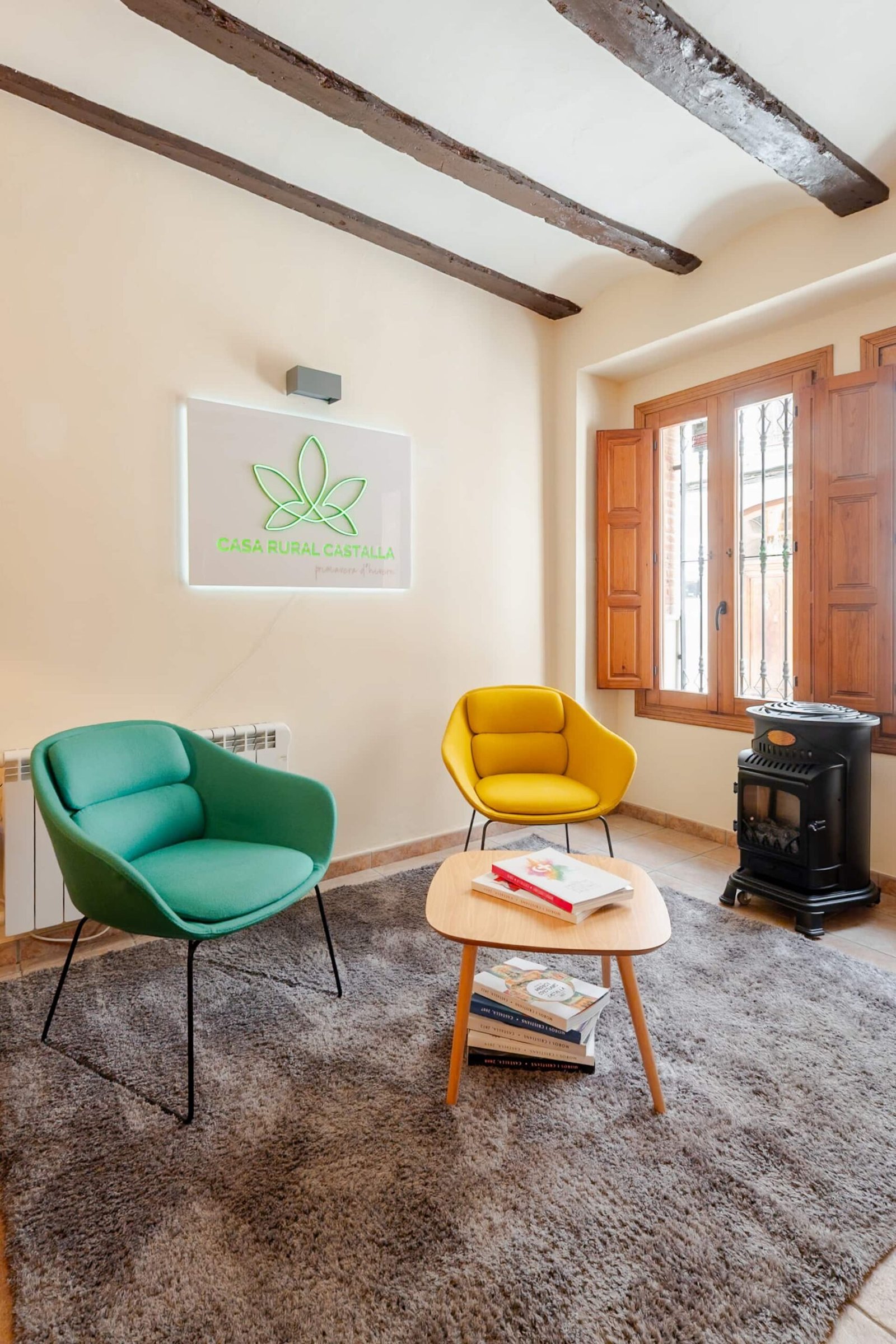 La Tardor lounge at Casa Rural Castalla, with its colourful armchairs, wood-burning stove and the house sign