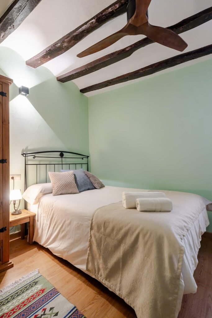 Lit de la chambre verte de Casa Rural Castalla avec serviettes de bain et fenêtre en bois
