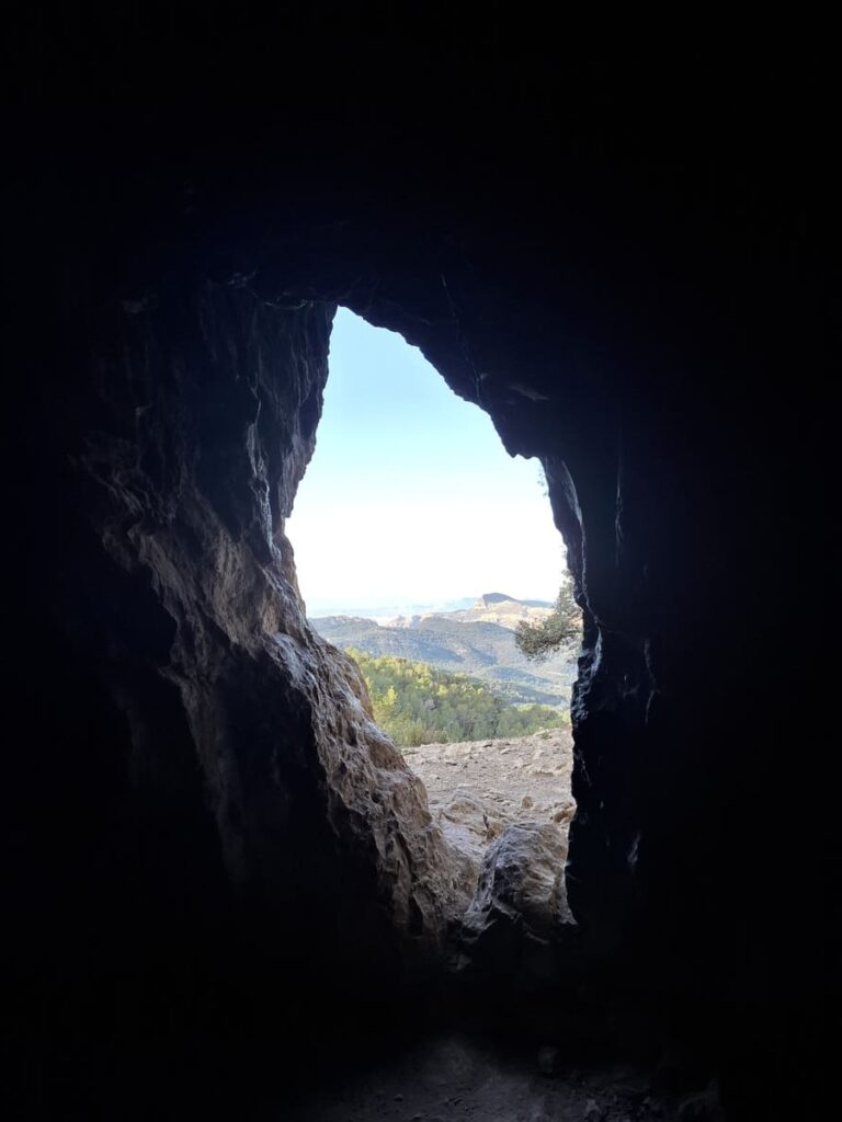 Interior misterioso de la Cova de Mossén Francés con luces y sombras resaltando formaciones rocosas.