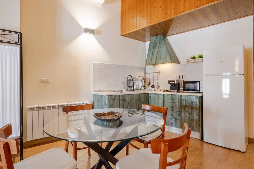 Cocina propia del apartamento de Casa Rural Castalla con mesa de cristal y muebles en verde