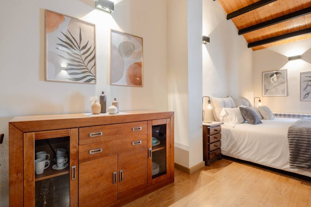 Aparador de madera del apartamento de Casa Rural Castalla, con la cama al fondo