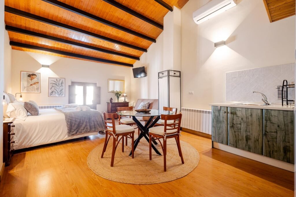 Apartamento de Casa Rural Castalla con cama, mesa de comedor redonda y cocina propia bajo el techo de madera