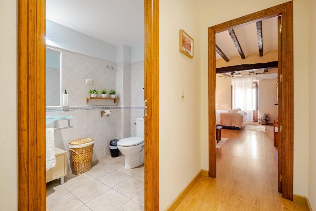 Baño completo de Casa Rural Castalla en tonos claros, con lavabo de cristal, espejo y sanitarios