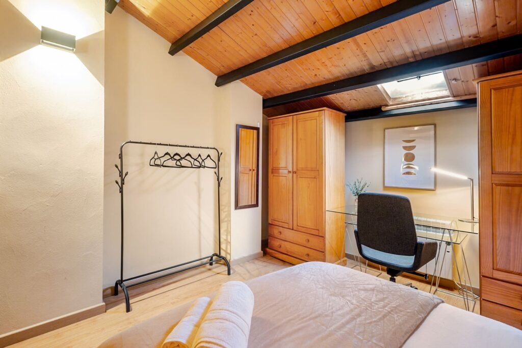 Buhardilla de Casa Rural Castalla con armario, escritorio y perchero bajo el techo de madera