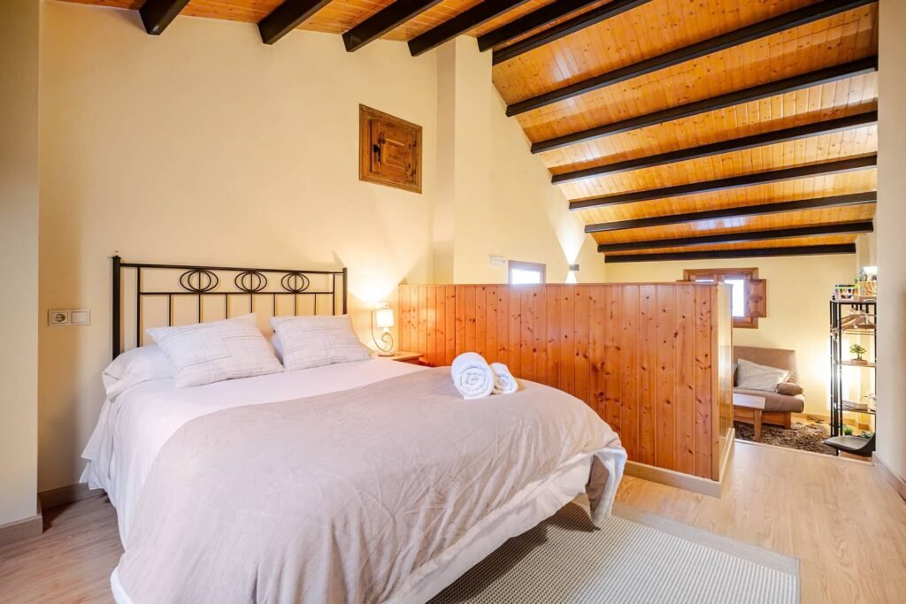Cama de la buhardilla de Casa Rural Castalla, separada por un tabique de madera de la zona de estar