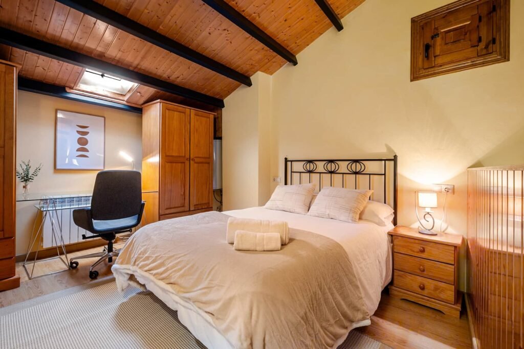 Dormitorio de la buhardilla de Casa Rural Castalla con cama, escritorio, armario y ventana de tejado