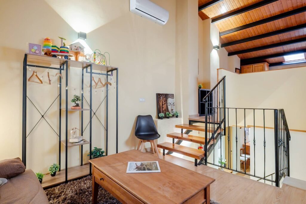 Zona de estar de la buhardilla de Casa Rural Castalla con estantería, mesa baja y la escalera de acceso