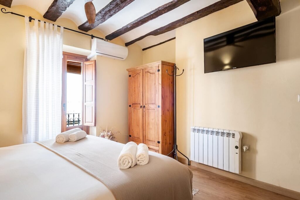 Habitación principal de Casa Rural Castalla con vigas de madera vistas, cama doble y armario de madera