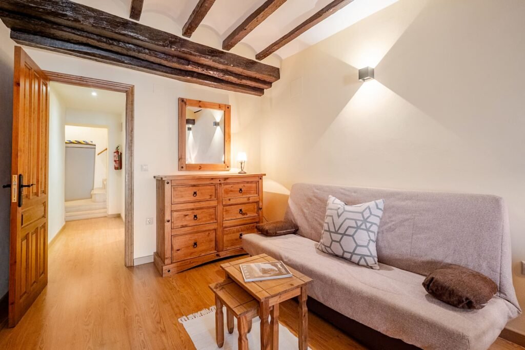 Zona de sofá y cómoda con espejo de la habitación principal de Casa Rural Castalla