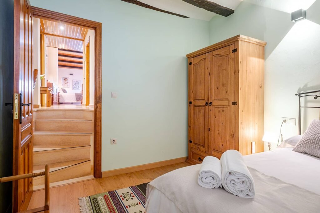 Habitación verde de Casa Rural Castalla con la puerta abierta al rellano y la alfombra kilim