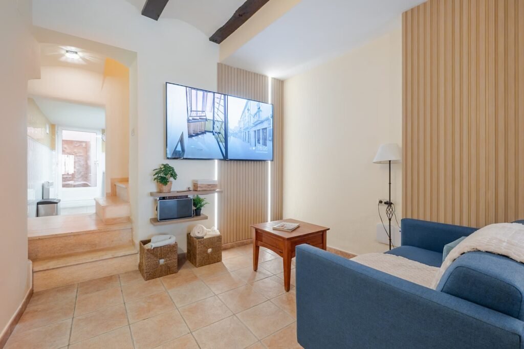 Salón de Casa Rural Castalla con sofá azul, televisión y acceso a las escaleras