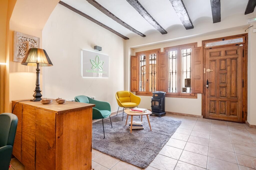 La Tardor de Casa Rural Castalla vista desde el aparador de madera, con los sillones y la puerta de entrada